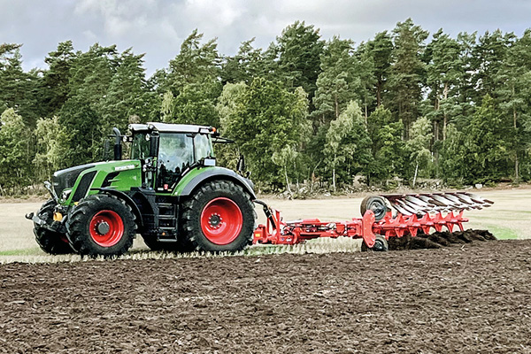 Grön Fendt-traktor med en röd Kuhn-plog på en åker.